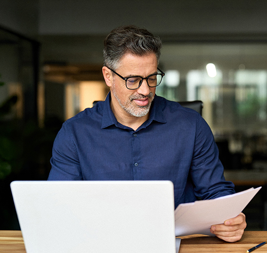 Ein Mann mit einer Brille schaut auf ein Blatt Papier.