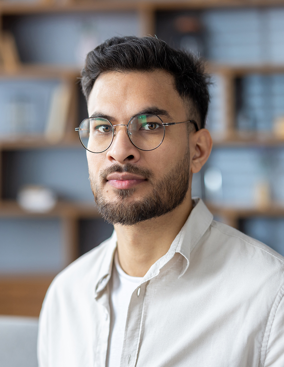 Eine Person mit einer Brille und einer eckigen Gesichtsform.