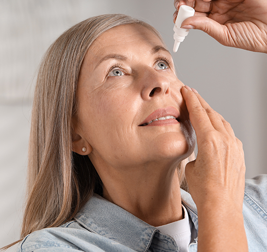 Eine Frau macht sich Augentropfen in die Augen.