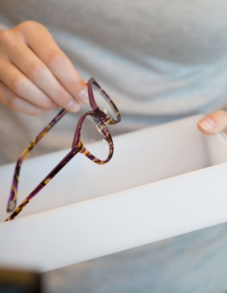 Eine Person holt eine Brille aus einem Karton.