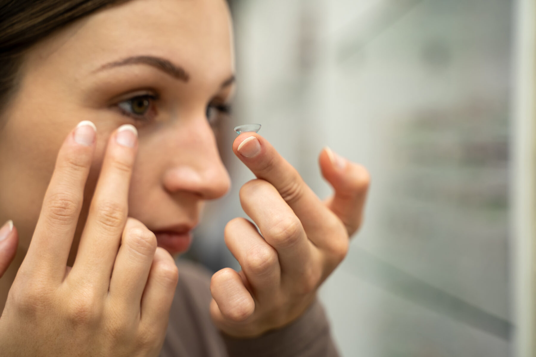 Eine Frau setzt sich eine Kontaktlinse ins Auge