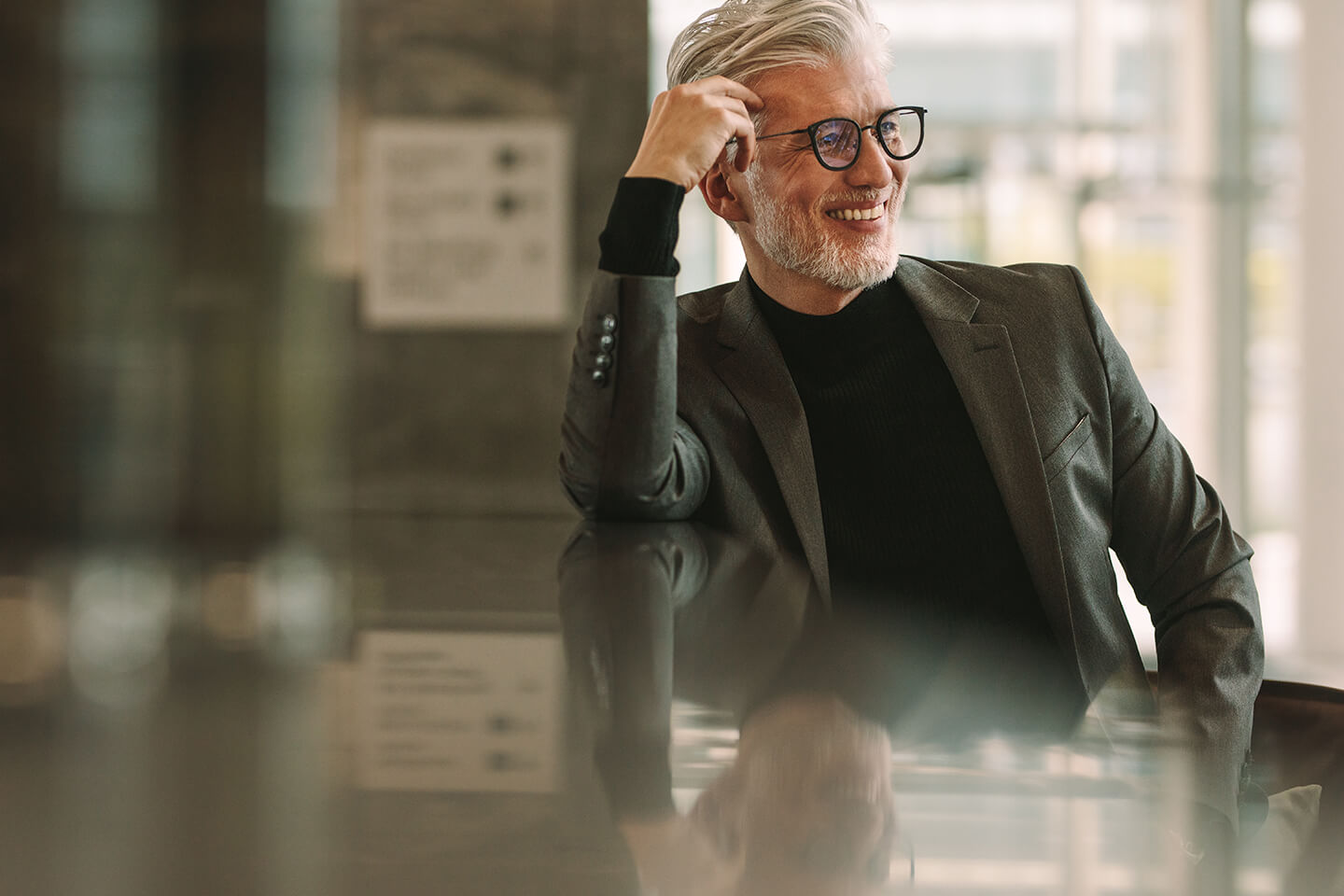 optik-zentrum-berlin-header-brillen Ein Mann mit einer schwarzen Brille sitzt an einem Tisch.