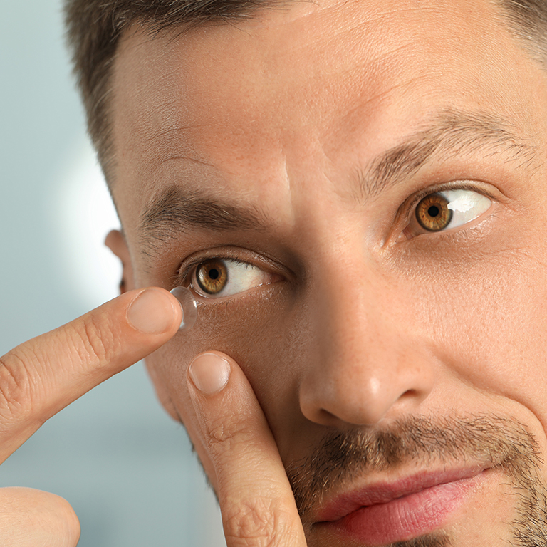 Ein Mann setzt sich eine Kontaktlinse ins Auge
